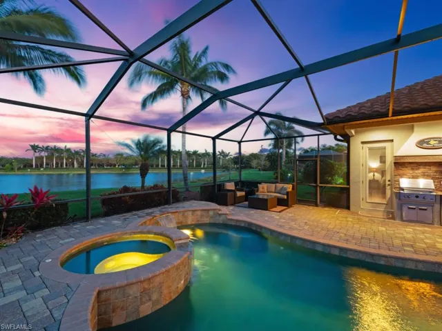 Pool at dusk with a patio area, an outdoor living space, a water view, exterior kitchen, and a lanai