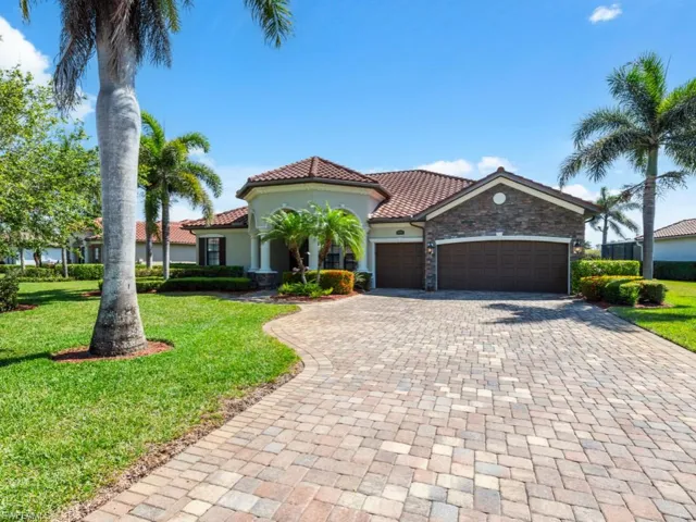 Mediterranean / spanish house with stone siding, a tile roof, decorative driveway, a front yard, and a garage