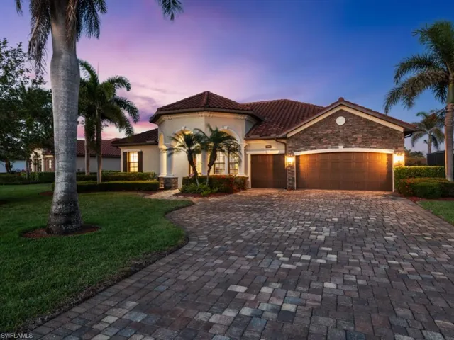 Mediterranean / spanish house with stone siding, a tiled roof, decorative driveway, a lawn, and a garage