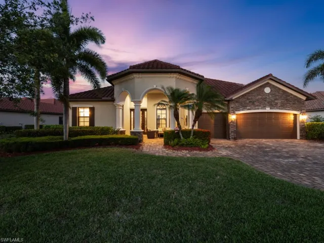 Mediterranean / spanish house with stucco siding, a yard, decorative driveway, a garage, and stone siding