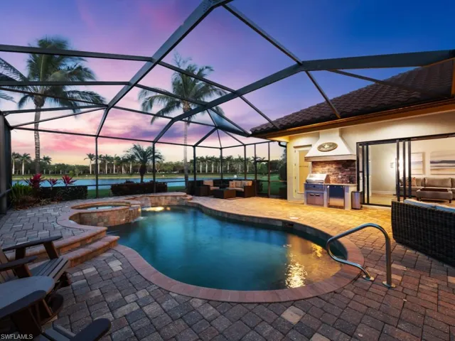 Pool at dusk featuring outdoor lounge area, an outdoor kitchen, a pool with connected hot tub, and a patio area