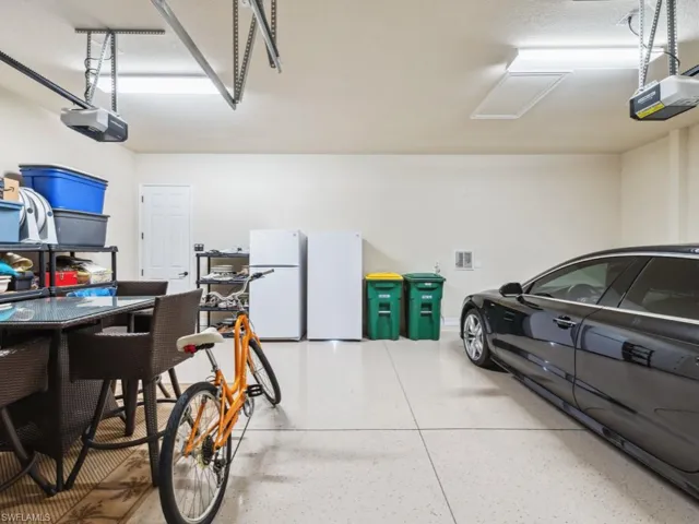 Garage with visible vents, freestanding refrigerator, and a garage door opener