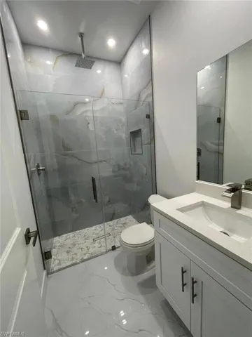 Bathroom with vanity, toilet, and a shower with shower door