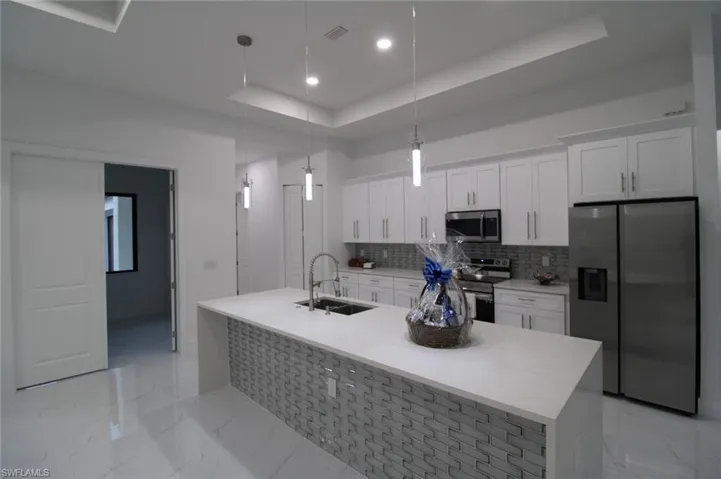 Kitchen featuring white cabinetry, sink, decorative light fixtures, and stainless steel appliances