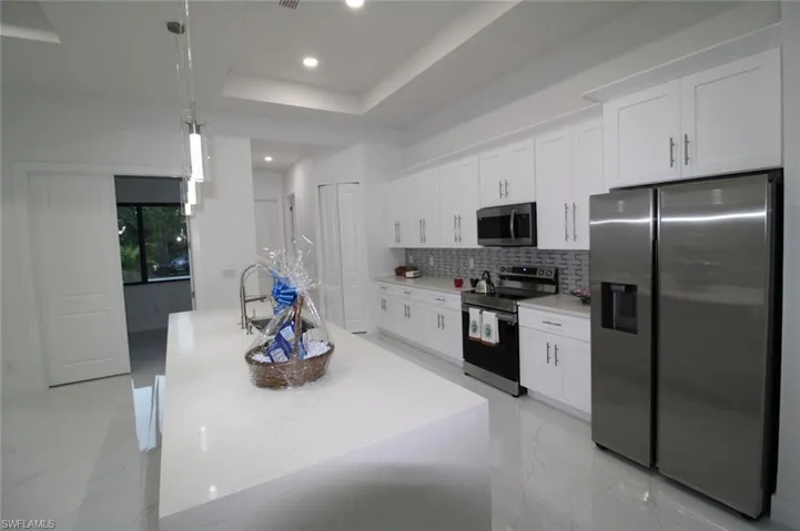 Kitchen featuring a kitchen island with sink, white cabinets, and appliances with stainless steel finishes