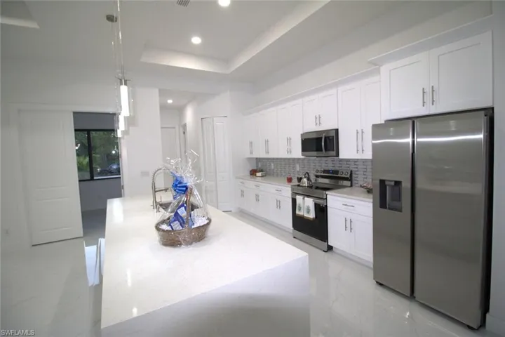 Kitchen with stainless steel appliances, white cabinetry, and a kitchen island with sink