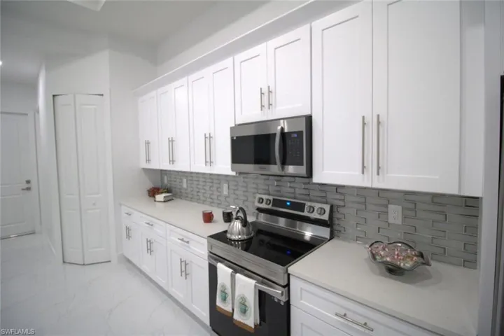 Kitchen featuring appliances with stainless steel finishes, white cabinets, and decorative backsplash