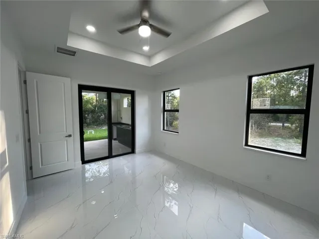 Spare room featuring a raised ceiling and ceiling fan