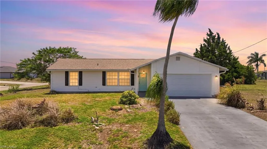 Single-story residence featuring a white exterior, attached garage, and a concrete driveway