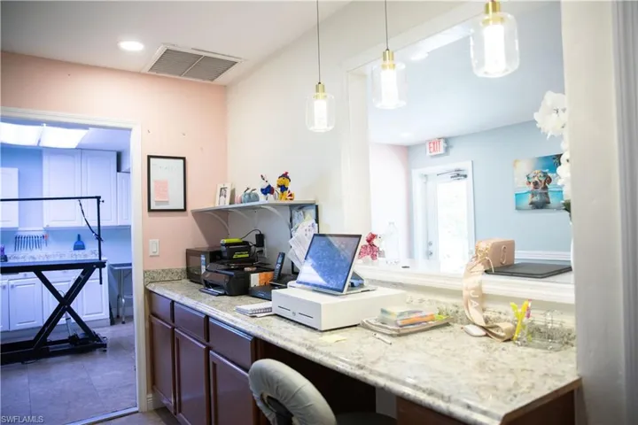Kitchen with light stone counters, hanging light fixtures, recessed lighting, black microwave, and built in study area