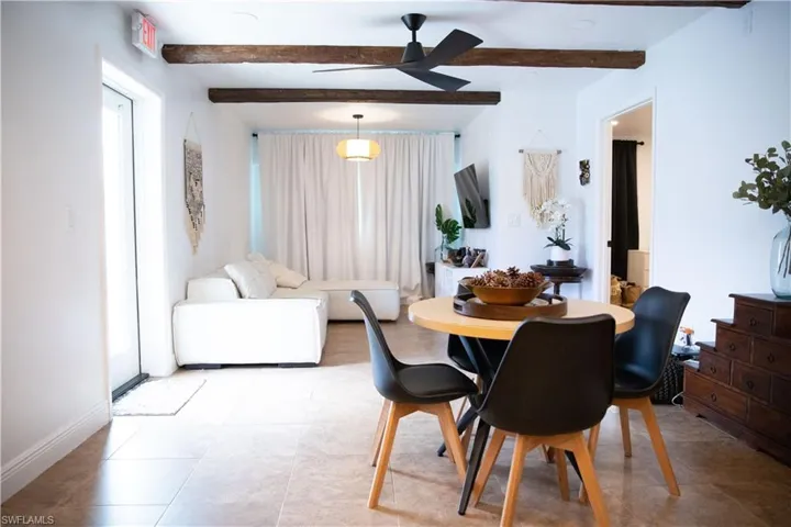 Tiled dining room with beamed ceiling and a ceiling fan