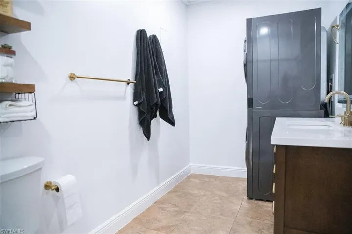 Bathroom with vanity, stacked washer and clothes dryer, and light tile patterned floors