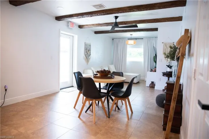 Dining space with beam ceiling, a ceiling fan, and light tile patterned floors
