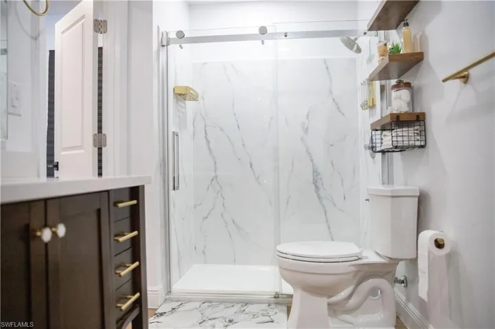 Full bath with vanity, a marble finish shower, and light marble finish flooring