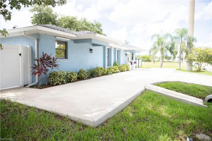 View of side of property featuring stucco siding and a gate