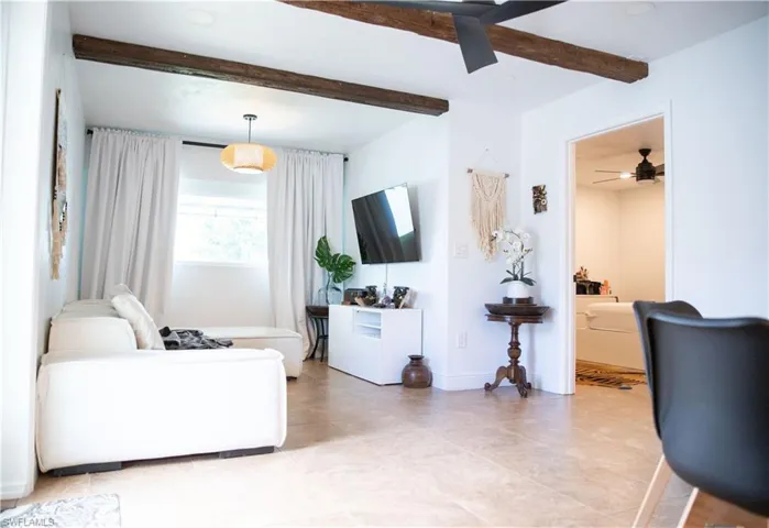 Living area featuring beam ceiling and a ceiling fan