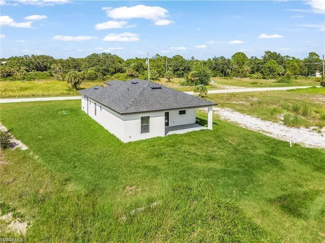 Back of property with a patio, a yard, stucco siding, and a shingled roof