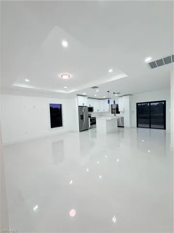 Unfurnished living room with a raised ceiling and recessed lighting