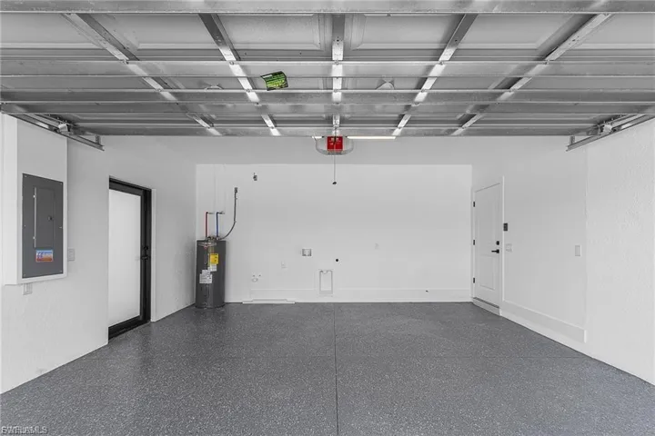 Garage featuring electric panel and electric water heater