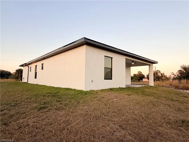 Property exterior at dusk featuring a lawn, stucco siding, and a patio area