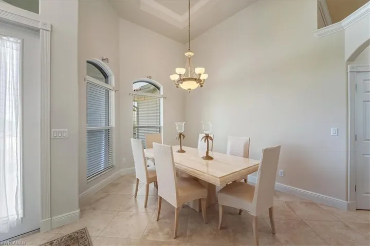 Dining area with high vaulted ceiling, a chandelier, light tile patterned floors, and arched walkways