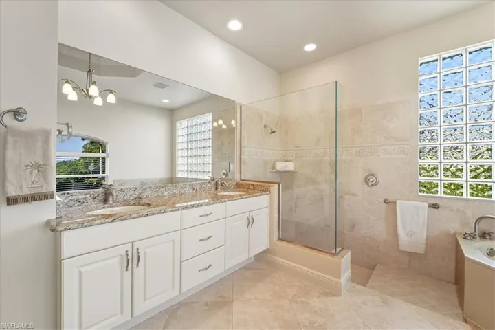 Full bath featuring double vanity, a garden tub, a walk in shower, light tile patterned floors, and recessed lighting