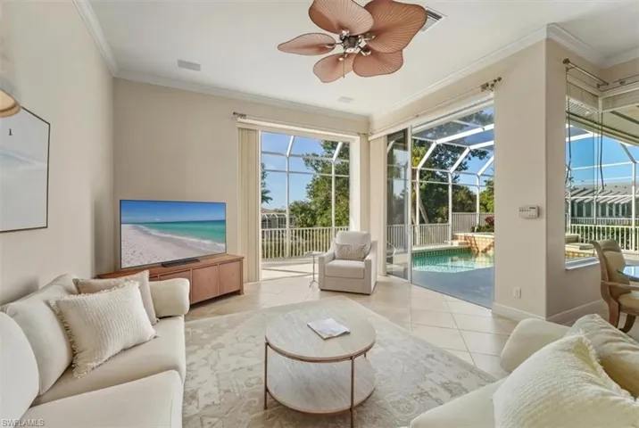 Tiled living area with a sunroom, ornamental molding, and ceiling fan