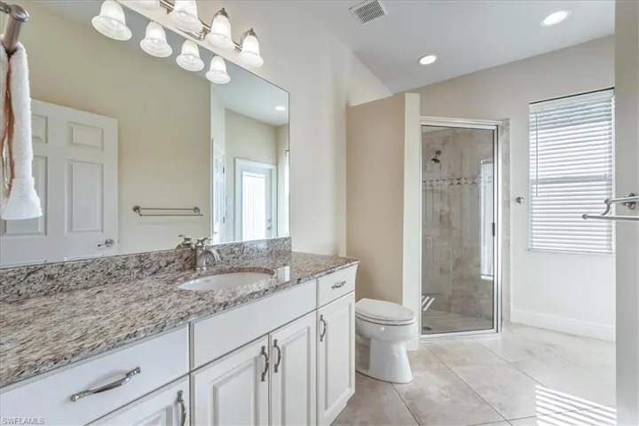 Full bathroom with vanity, a shower stall, light tile patterned floors, and recessed lighting