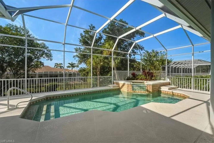 View of pool with glass enclosure, a sunroom, a patio area, and a pool with connected hot tub