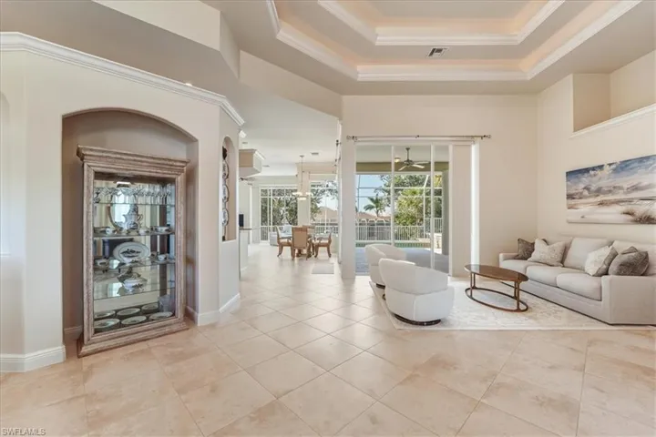Living room with crown molding, a tray ceiling, and light tile patterned flooring