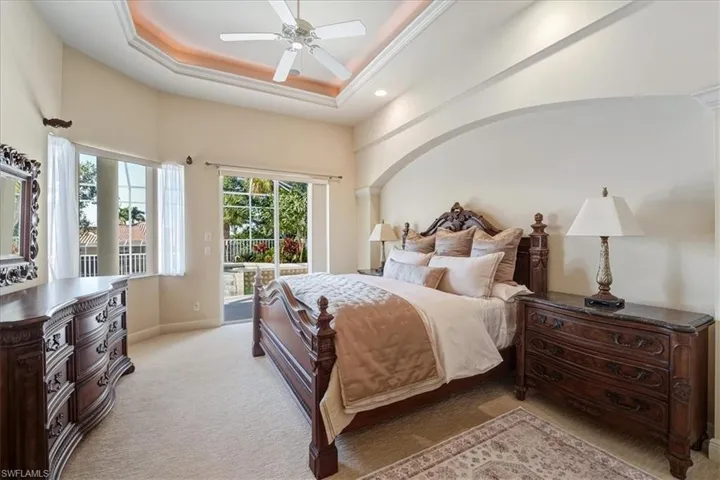 Bedroom with light carpet, a tray ceiling, ceiling fan, and access to exterior