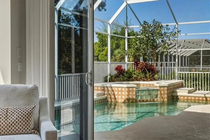 Swimming pool with a lanai, a patio area, a sunroom, and an in-ground hot tub