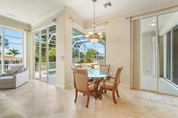 Tiled dining space featuring ornamental molding and a chandelier