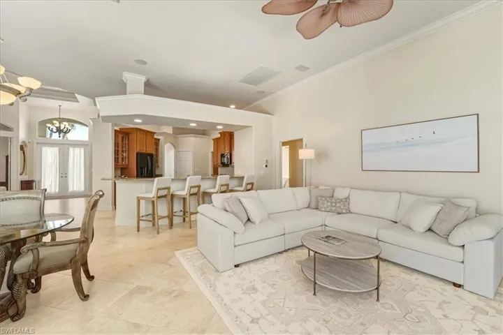 Living room featuring crown molding, arched walkways, a chandelier, french doors, and ceiling fan