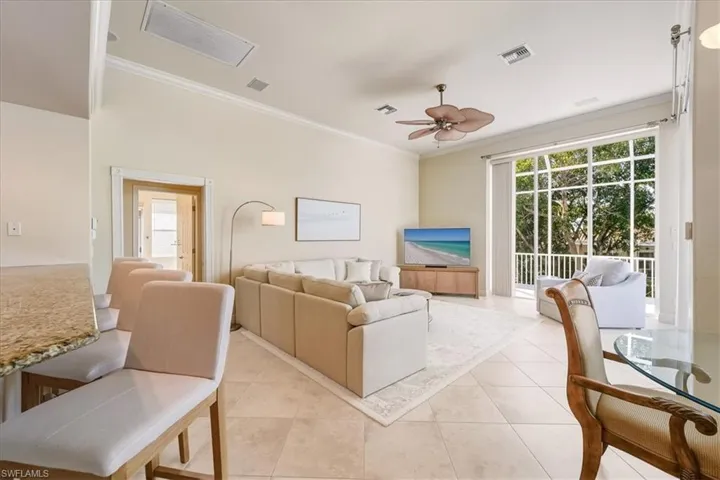 Living room featuring ornamental molding, light tile patterned floors, ceiling fan, and healthy amount of natural light