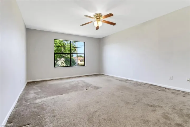 Carpeted empty room featuring ceiling fan and baseboards