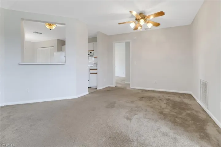 Empty room featuring visible vents, baseboards, a ceiling fan, and light carpet