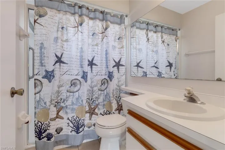 Bathroom with toilet, vanity, tile patterned flooring, and a shower with curtain