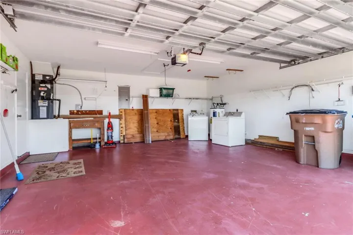 Garage featuring independent washer and dryer, a garage door opener, electric panel, and heating unit