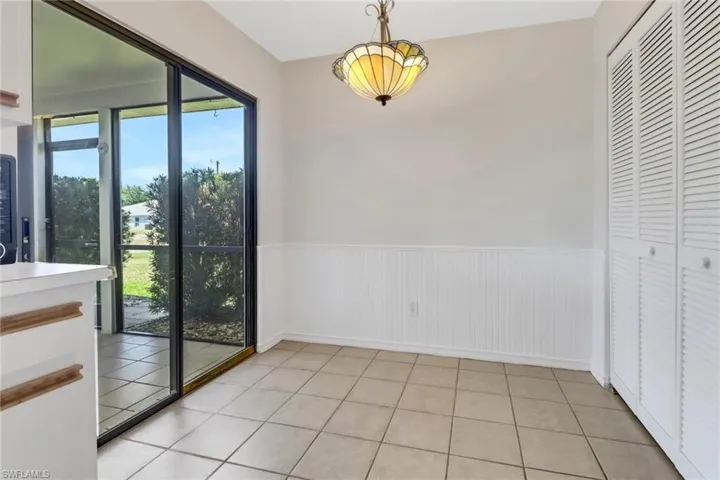 Unfurnished dining area with light tile patterned floors, baseboards, and wainscoting