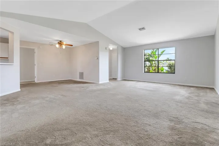 Unfurnished room featuring visible vents, baseboards, vaulted ceiling, and a ceiling fan