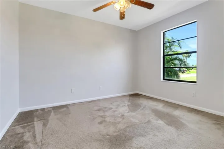 Carpeted spare room featuring baseboards and a ceiling fan
