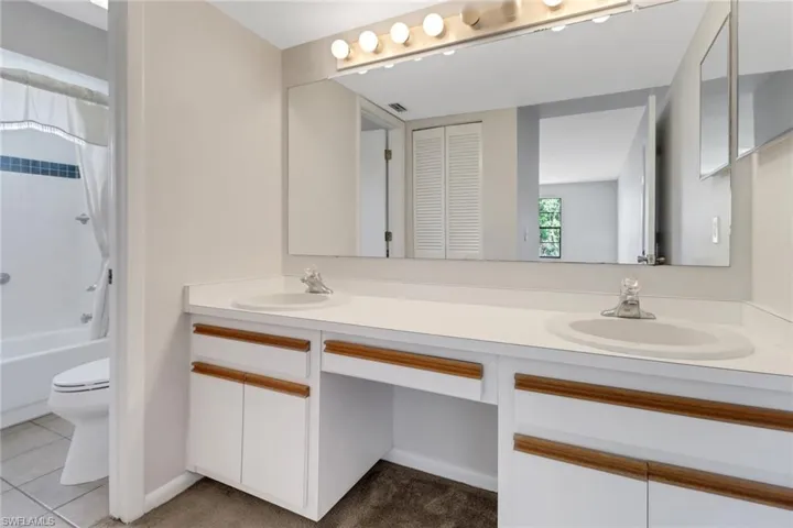 Full bathroom with a sink, toilet, double vanity, and shower / bathing tub combination