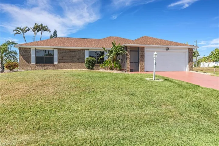 Single story home featuring a garage, driveway, a front lawn, and brick siding