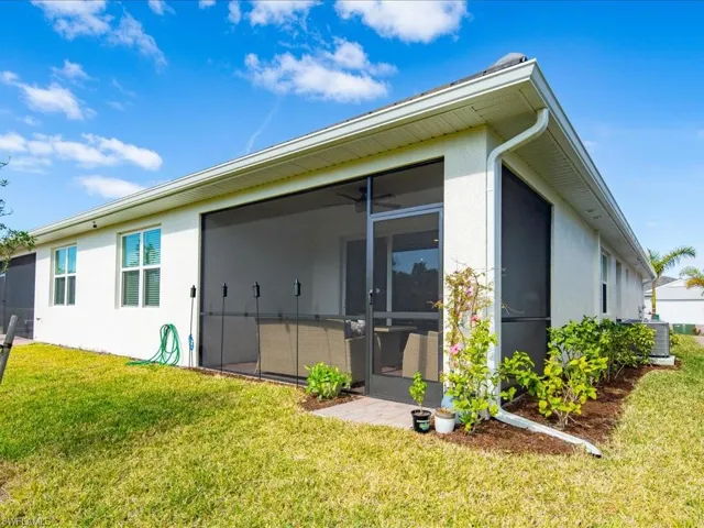 Rear view of house featuring a sunroom, central AC unit, and a yard