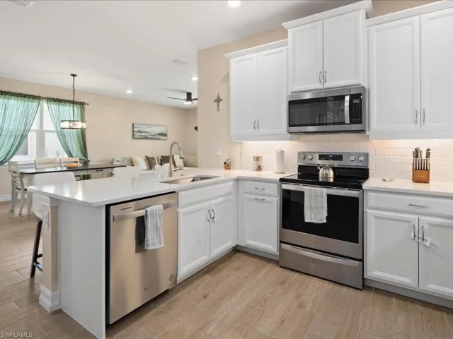 Kitchen featuring white cabinets, kitchen peninsula, sink, and appliances with stainless steel finishes