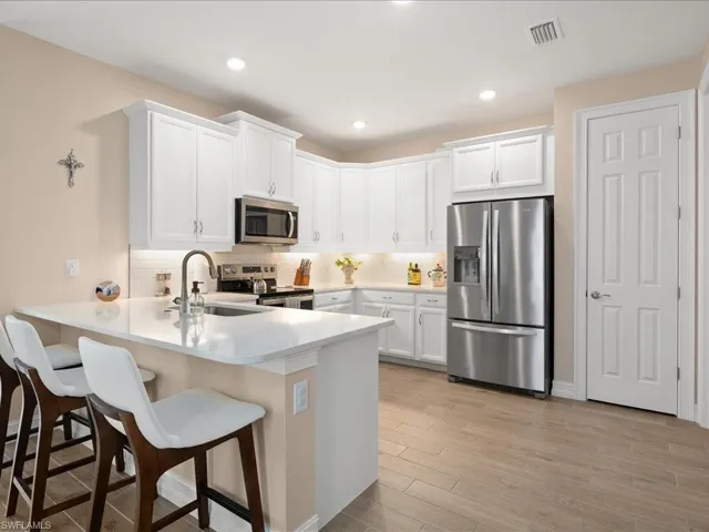 Kitchen with kitchen peninsula, sink, white cabinets, and appliances with stainless steel finishes