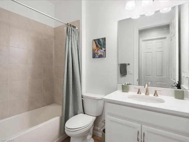 Full bathroom featuring vanity, toilet, and shower / bathtub combination with curtain