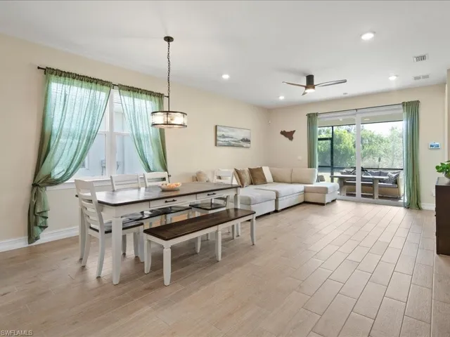 Dining area featuring ceiling fan with notable chandelier and light wood-type flooring