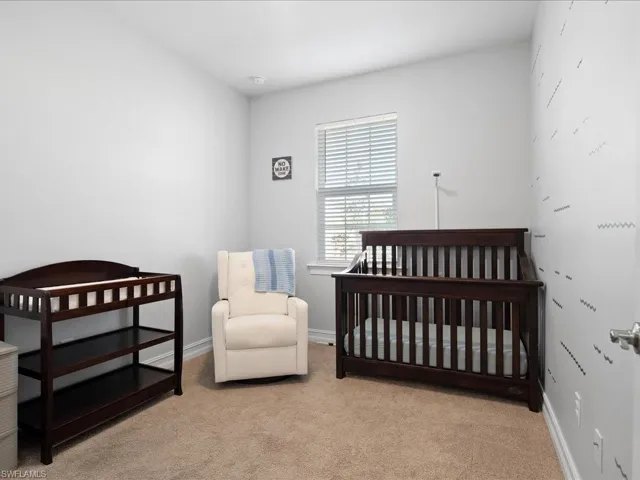 Bedroom featuring light carpet and a nursery area